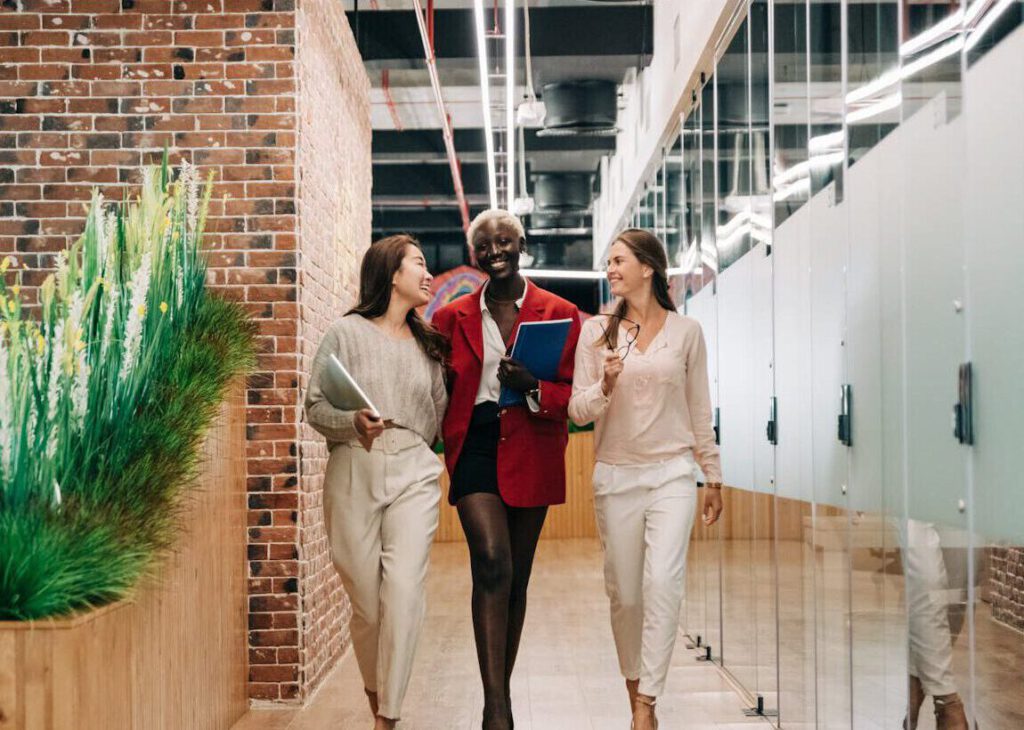 Mitarbeitende gehen lachend durch ein Büro – Symbol für Motivation und Wohlbefinden durch Betriebliches Gesundheitsmanagement